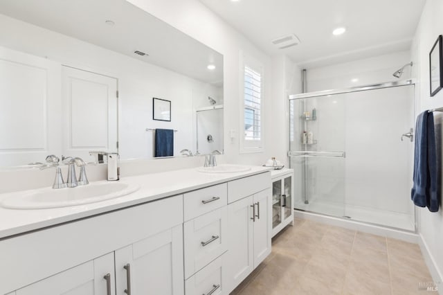 bathroom with a shower with door, tile patterned floors, and vanity