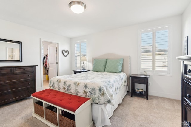 bedroom featuring a walk in closet, a closet, and light colored carpet