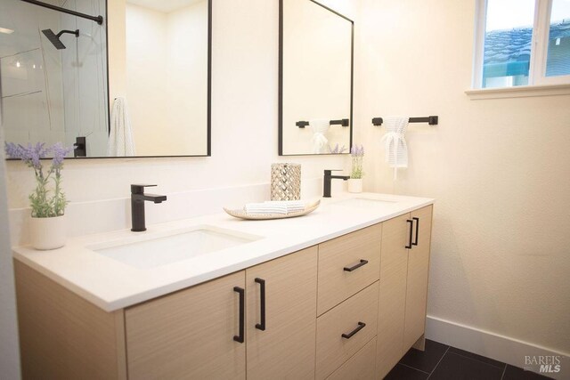 bathroom with double vanity, tile patterned flooring, baseboards, and a sink