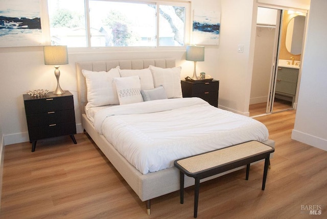 bedroom with light wood-type flooring, a closet, baseboards, and a sink