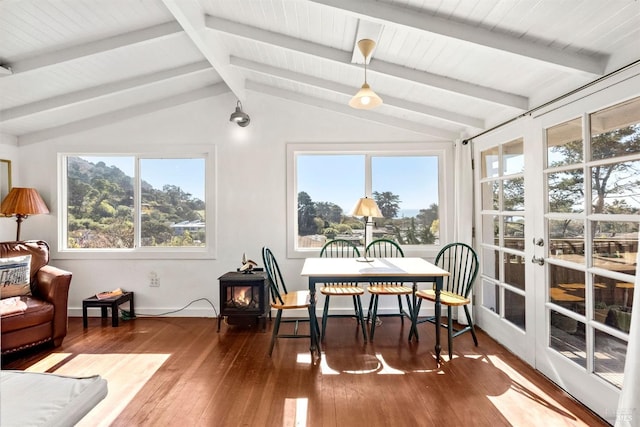 sunroom with a wood stove, a wealth of natural light, and vaulted ceiling with beams