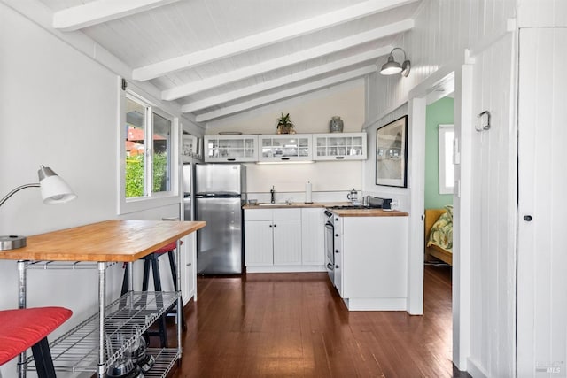 kitchen with white cabinetry, wood counters, vaulted ceiling with beams, and stainless steel refrigerator