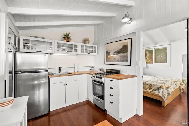 kitchen featuring sink, stainless steel appliances, white cabinetry, and lofted ceiling with beams