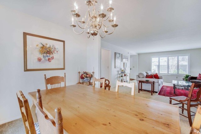 dining space featuring carpet and a chandelier