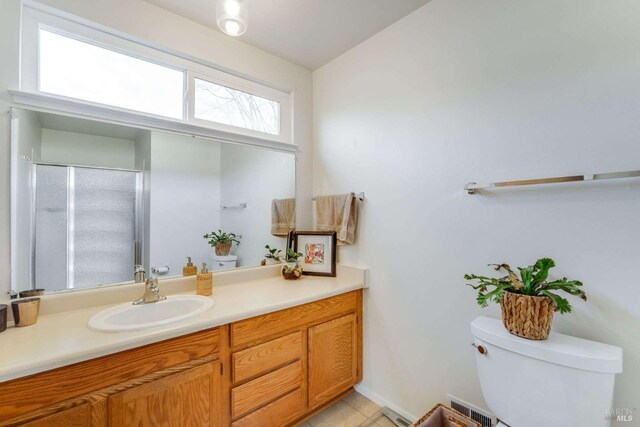 bathroom featuring tile patterned flooring, toilet, vanity, and a shower with shower door