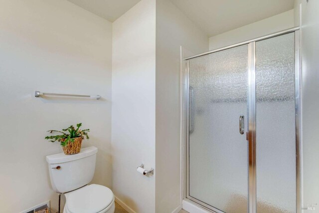 bathroom featuring toilet and a shower with door