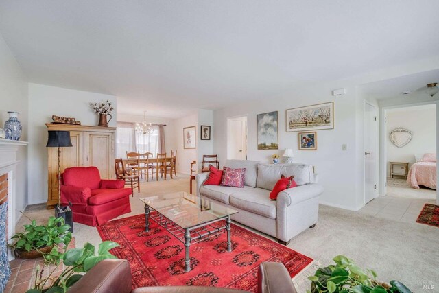 living room with a brick fireplace, light colored carpet, and a notable chandelier