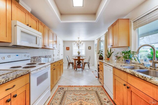 kitchen featuring white appliances, light stone countertops, a notable chandelier, light tile patterned floors, and sink