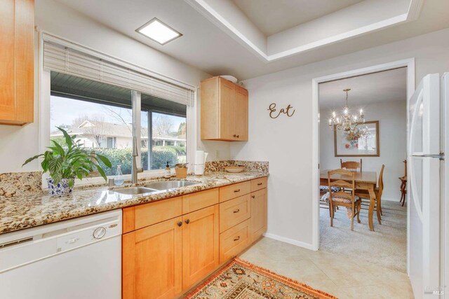 kitchen featuring light brown cabinets, white appliances, light carpet, and a notable chandelier