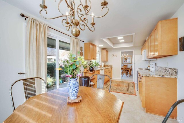 dining room with a tray ceiling, light tile patterned floors, and a chandelier