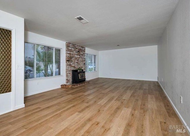 unfurnished living room featuring light hardwood / wood-style floors and a wood stove