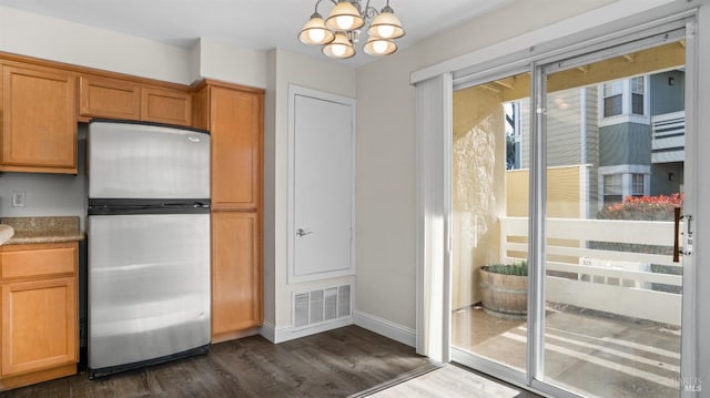 kitchen with a notable chandelier, stainless steel fridge, and dark hardwood / wood-style flooring