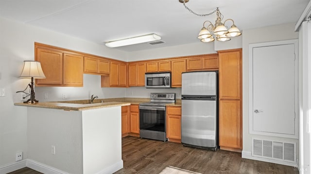 kitchen featuring kitchen peninsula, an inviting chandelier, dark hardwood / wood-style flooring, appliances with stainless steel finishes, and sink