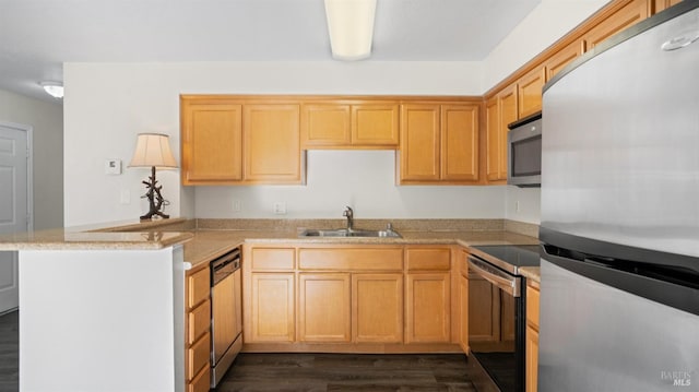 kitchen with sink, light stone counters, kitchen peninsula, dark hardwood / wood-style floors, and appliances with stainless steel finishes