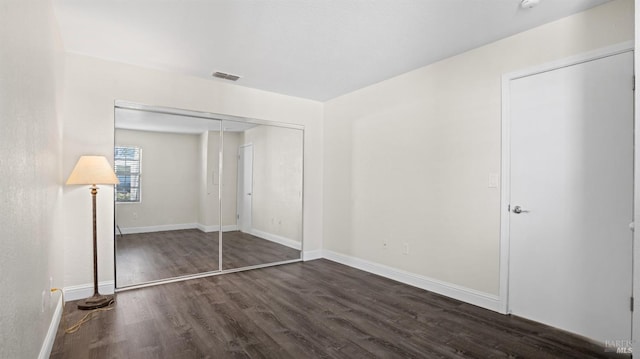 unfurnished bedroom featuring a closet and dark hardwood / wood-style floors