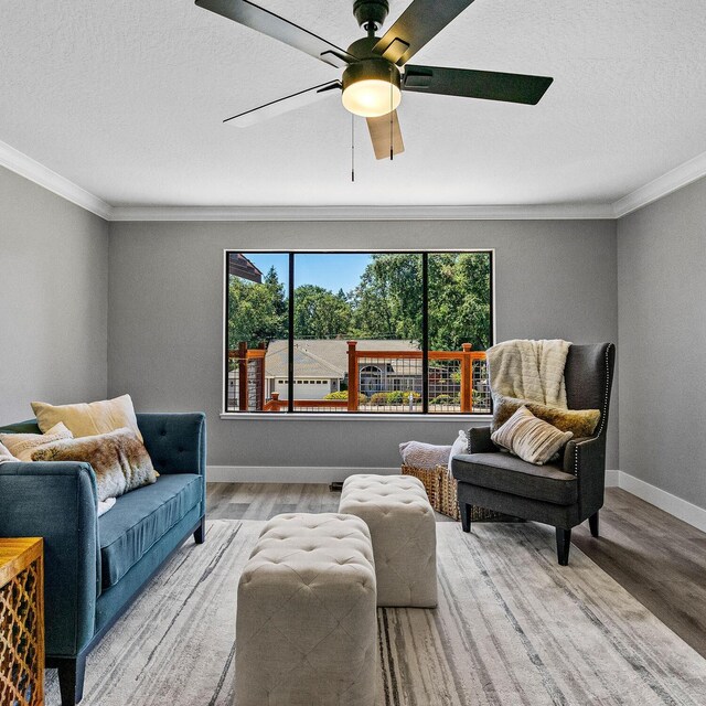 living room featuring ornamental molding, light hardwood / wood-style floors, and ceiling fan