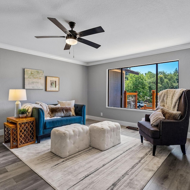 living room featuring crown molding, ceiling fan, wood-type flooring, and a textured ceiling