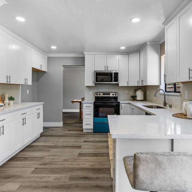 kitchen featuring white cabinetry, black range with electric stovetop, sink, and kitchen peninsula