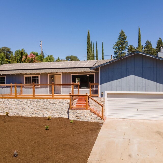 ranch-style home featuring a garage and solar panels