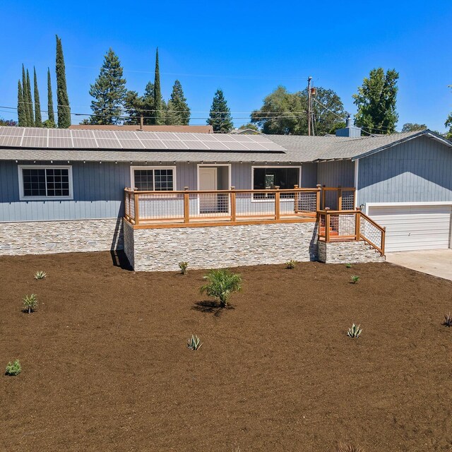 single story home with a garage and solar panels