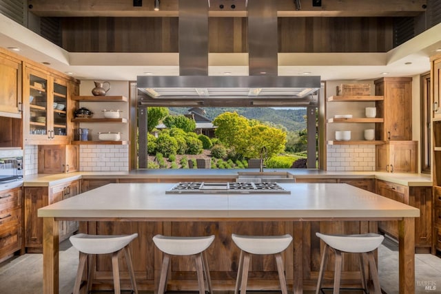 bar featuring sink, stainless steel gas cooktop, backsplash, and island range hood