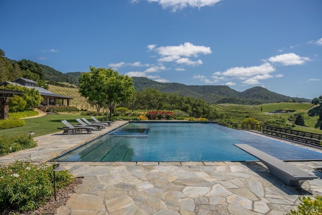 view of swimming pool featuring a diving board, a patio area, and a mountain view