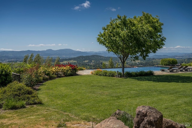 view of community featuring a lawn and a water and mountain view