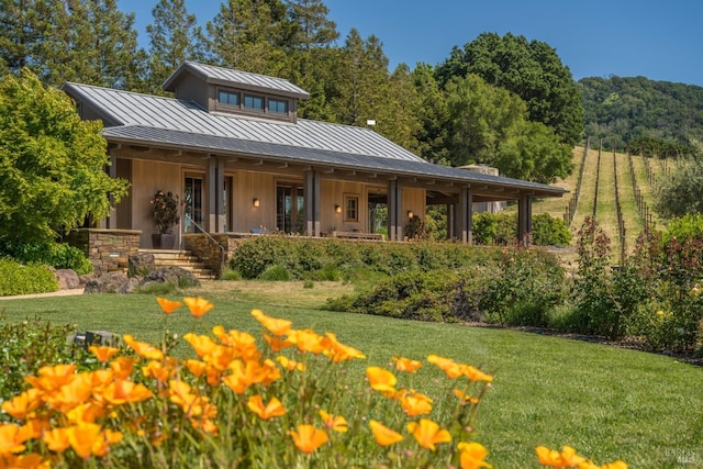 back of property featuring board and batten siding, a standing seam roof, a lawn, and metal roof