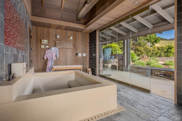 bathroom featuring a high ceiling, wood ceiling, wood walls, and beamed ceiling