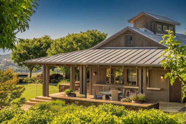 rear view of property featuring a lawn, a patio, a standing seam roof, and metal roof
