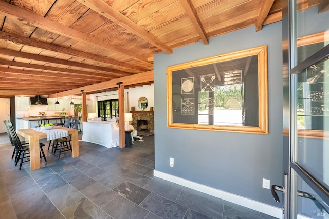 unfurnished dining area with beam ceiling, wood ceiling, and a fireplace