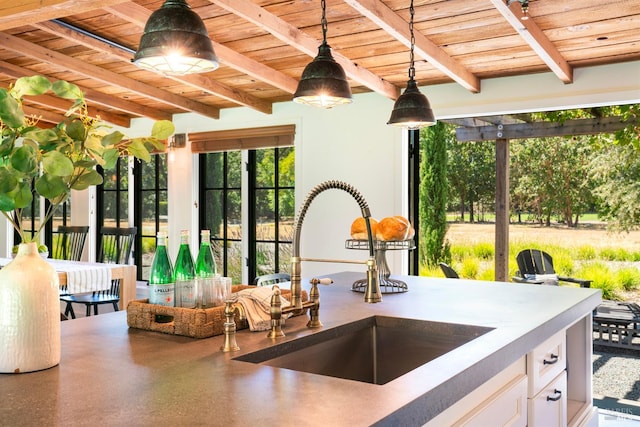 interior space with sink, wooden ceiling, white cabinetry, and beamed ceiling