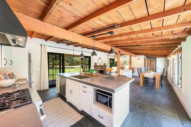 kitchen with sink, white cabinetry, beamed ceiling, a center island with sink, and pendant lighting