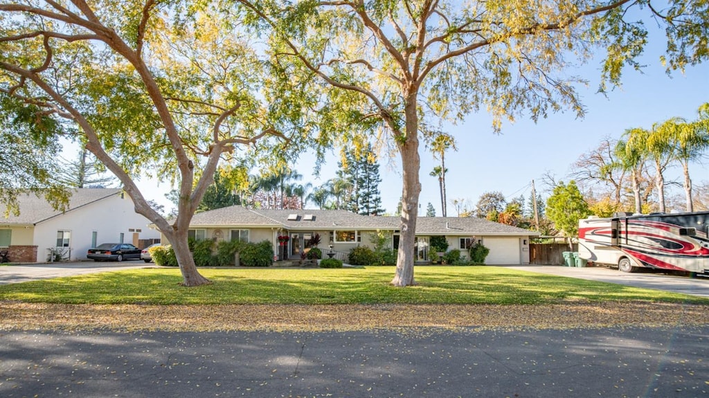 ranch-style home with concrete driveway and a front lawn