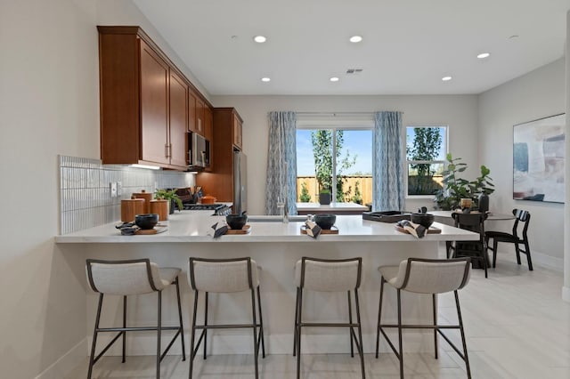 kitchen featuring appliances with stainless steel finishes, a breakfast bar, light countertops, and a peninsula