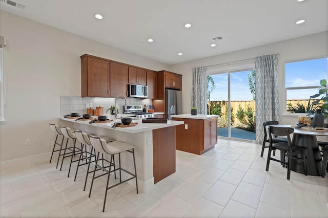 kitchen with a peninsula, visible vents, appliances with stainless steel finishes, and decorative backsplash