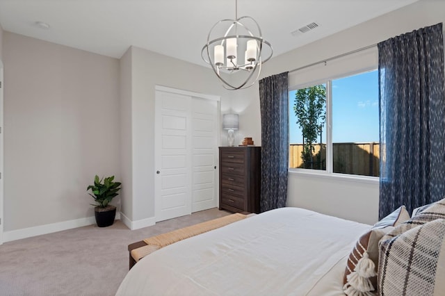 carpeted bedroom with a chandelier, a closet, visible vents, and baseboards