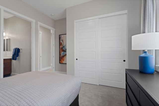 bedroom with ensuite bathroom, a closet, and light colored carpet