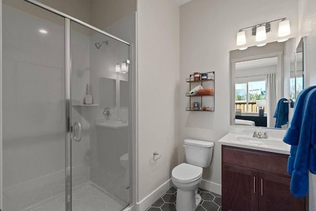 ensuite bathroom featuring vanity, a shower stall, toilet, and baseboards