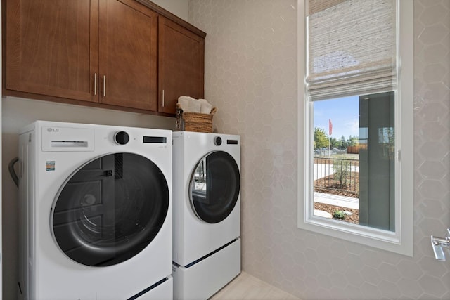 laundry room with a wealth of natural light, washing machine and clothes dryer, and cabinet space