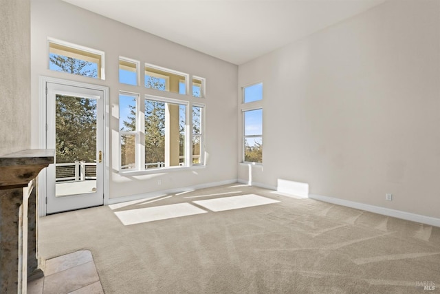 carpeted empty room with baseboards and a towering ceiling