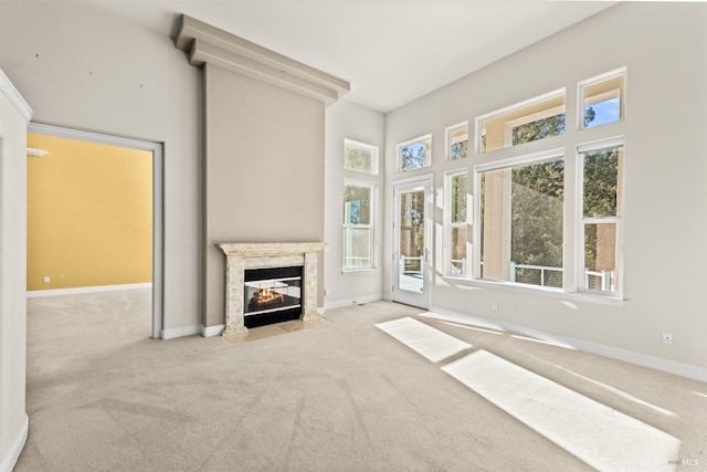 unfurnished living room featuring carpet, a fireplace, and baseboards
