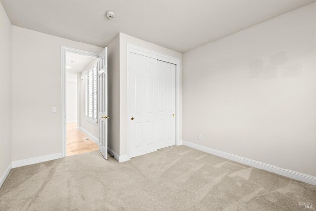 unfurnished bedroom with carpet, baseboards, and a closet
