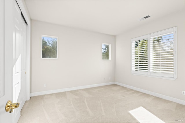 unfurnished bedroom featuring multiple windows, visible vents, and light carpet