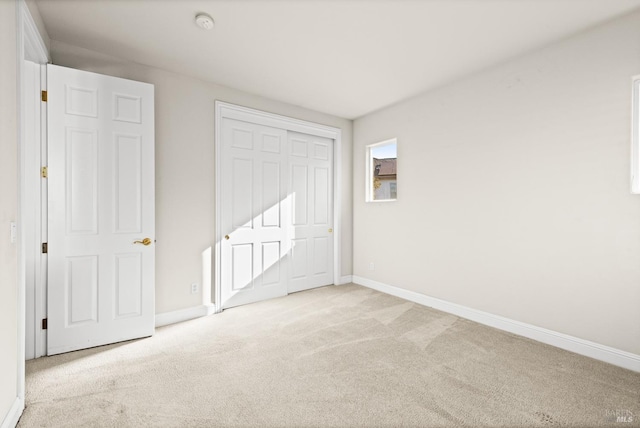 unfurnished bedroom with a closet, baseboards, and carpet flooring