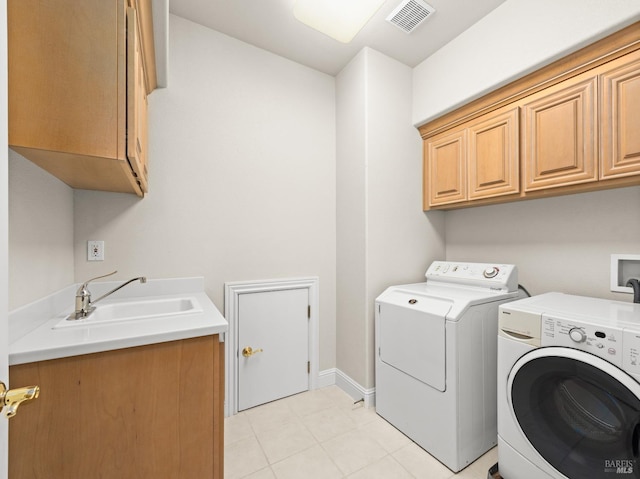 washroom with baseboards, visible vents, cabinet space, a sink, and washing machine and dryer