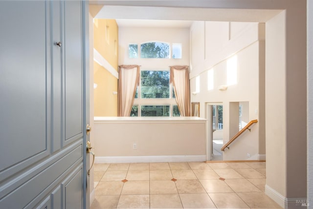 entrance foyer with light tile patterned floors, a high ceiling, and baseboards