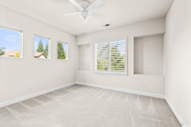 carpeted empty room featuring visible vents, baseboards, a healthy amount of sunlight, and ceiling fan