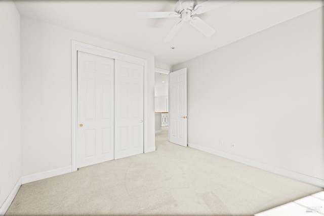 unfurnished bedroom featuring a ceiling fan, light colored carpet, baseboards, and a closet