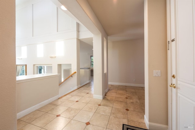 corridor featuring light tile patterned floors, a healthy amount of sunlight, and baseboards